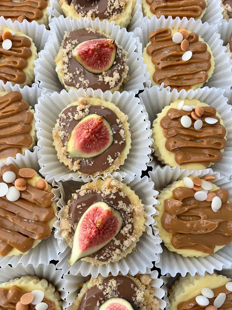 A tray of mini cheesecakes topped with caramel drizzle, chocolate and fresh fig halves